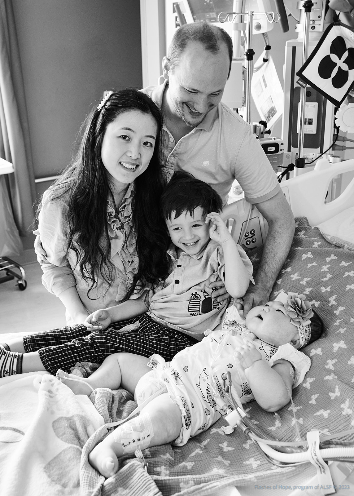 Black and white of Mommy and Daddy with Declan and Constance on a bed.